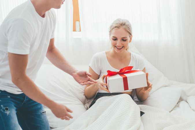 Woman receiving a gift in bedroom at home
