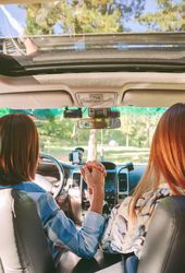 Happy women holding hands inside of car