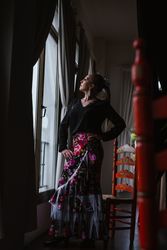 Woman dancer in suit for flamenco sitting and looking out window