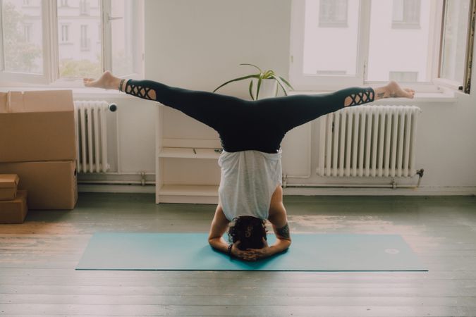 Fit woman practicing yoga pose and standing on head at home