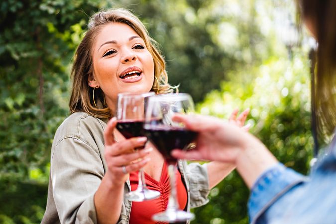 Happy young woman toasting with a glass of red wine