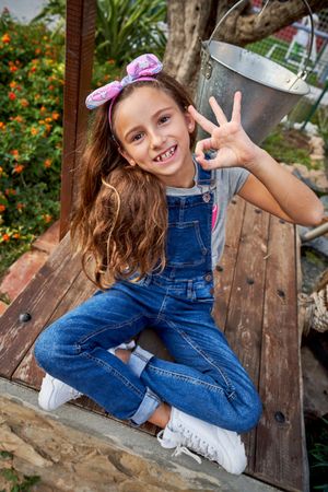 Smiling girl showing OK gesture on bench