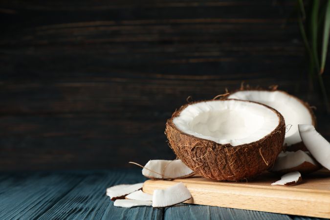Board with coconut on wooden background, space for text