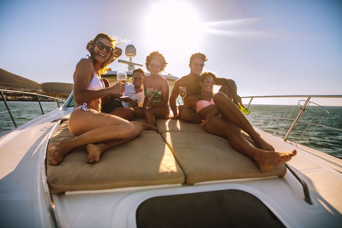 Group of happy young people sitting on yacht deck sailing in the sea