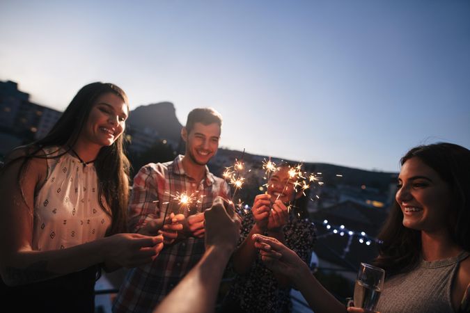 Group of friends enjoying rooftop party with sparklers