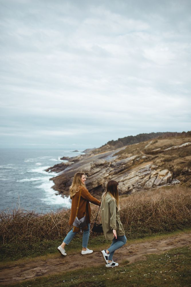 Happy female friends walking on trail at seaside