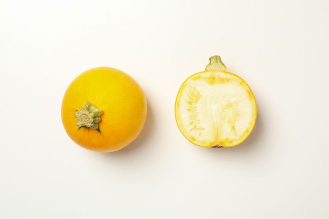 Round zucchini and half on neutral background