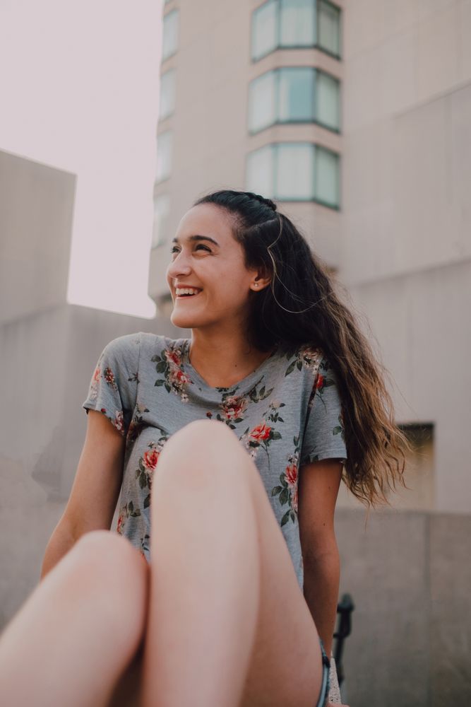 Smiling modern woman sitting on parapet