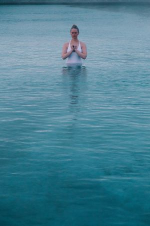 Woman in pool near sea and hills on shore