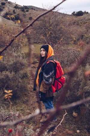 Hiker with backpack walking along pathway in autumn forest