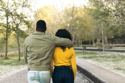 back view of a Black couple walking in a park