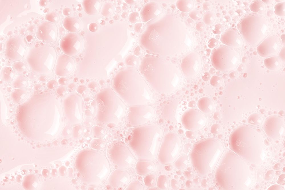 Light pink soap bubbles on liquid surface