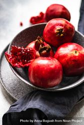 Dark bowl full of fresh whole pomegranates, vertical composition 4Z8Jn0