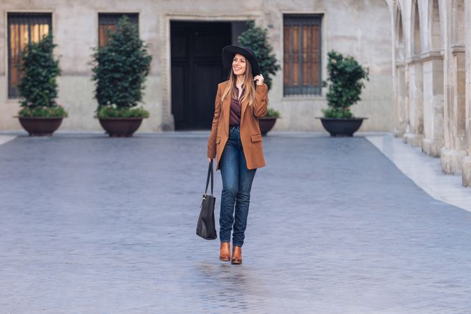 Gorgeous woman in fashionable outfit strolling on city street