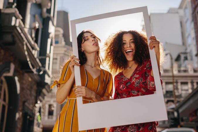 Beautiful women standing on a city street and holding a blank photo frame
