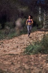 Serious athletic female jogging on path in woods