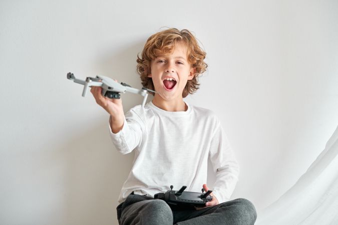 Excited child with toy drone on white background