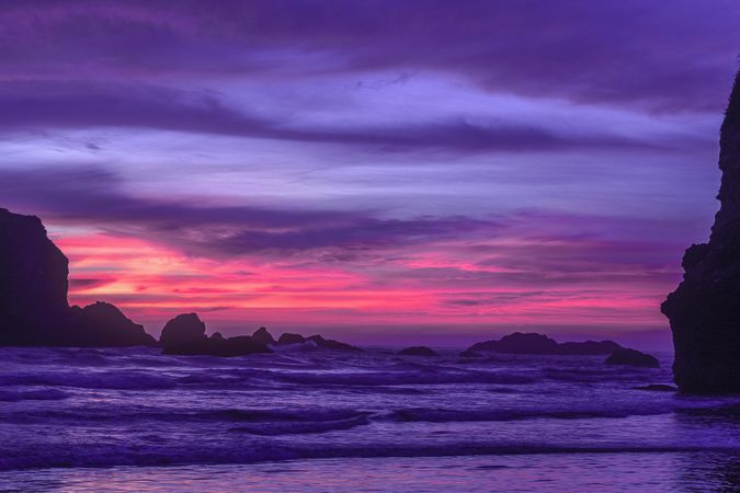 Looking out at scenic view of rocks in the Pacific Ocean at sunset