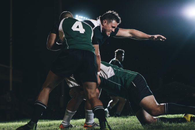 Rugby players competing in match under lights