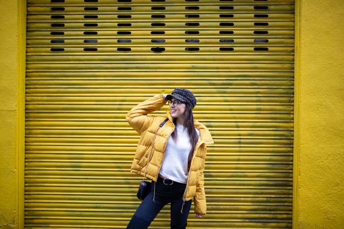 Trendy female standing near yellow wall on street