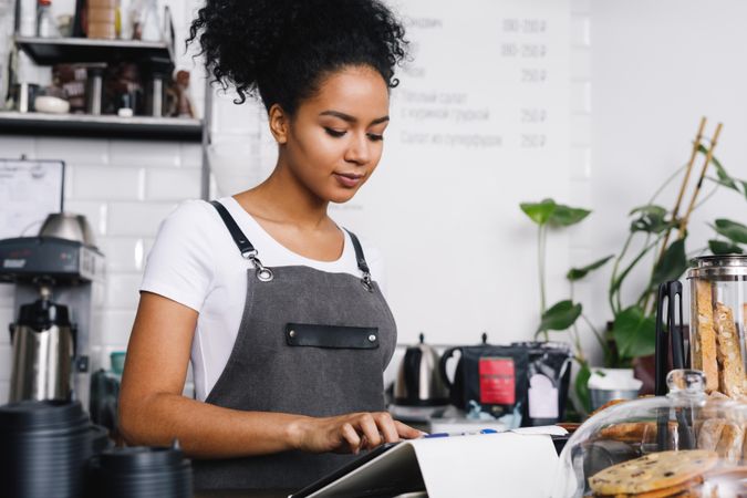 Barista looking down at tablet in coffee shop