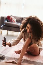Black woman taking selfie on floor