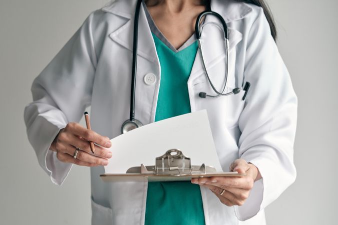 Faceless physician in medical uniform with clipboard and stethos