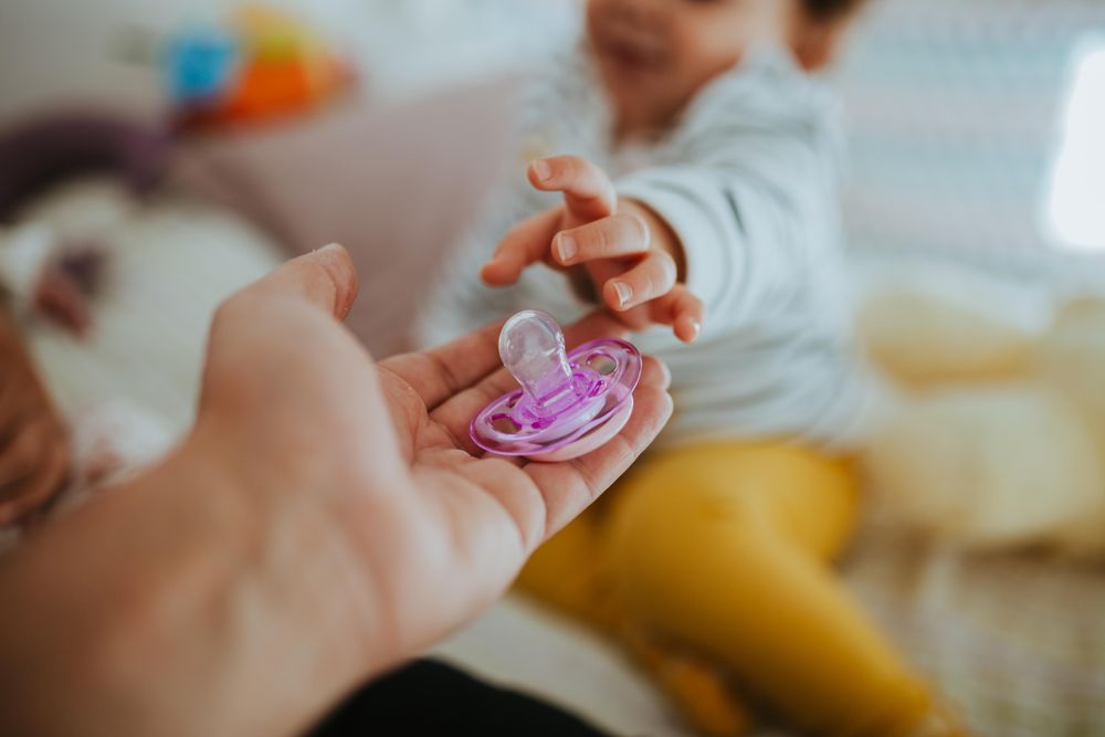 Close up of toddlers hand reaching out for a pacifier
