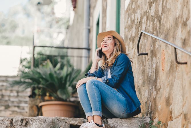 Woman with smartphone sitting on stone steps of stairs