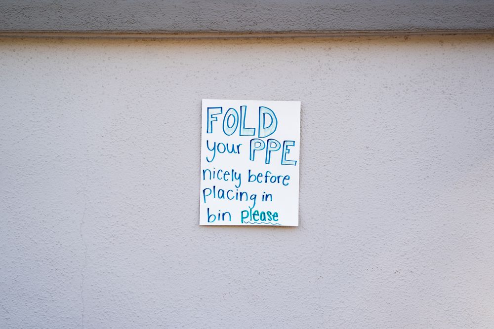 Handwritten sign for medical workers at public Covid testing site for PPE instructions