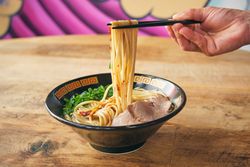 Crop person with noodles on chopsticks above delicious ramen