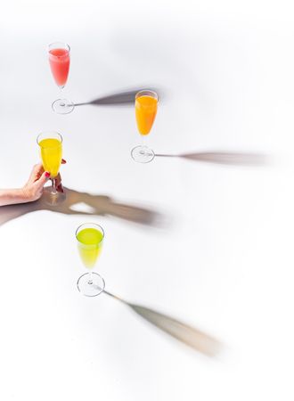 Hand and glasses of bright colorful drinks on table