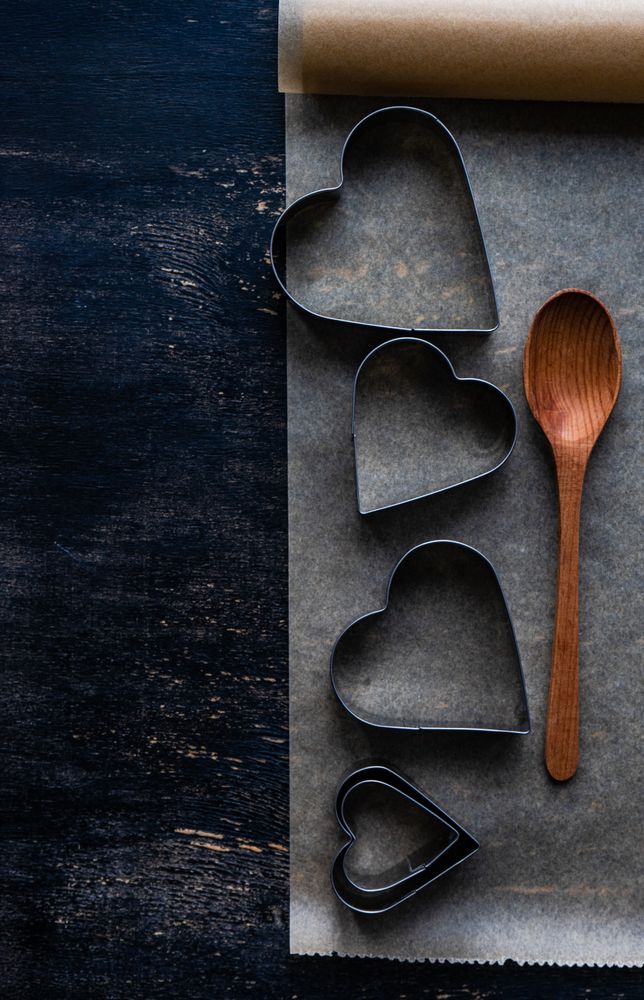 Heart shaped cookie cutters and baking equipment on parchment paper