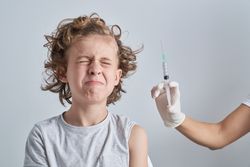 Boy closing eyes at syringe