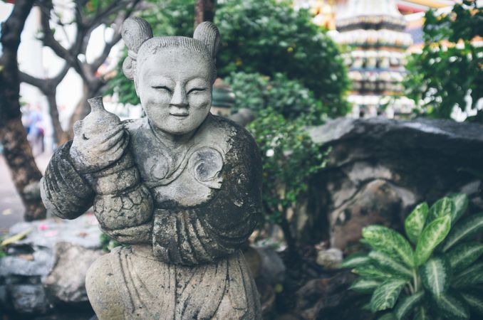 Shabby statue near stones in garden