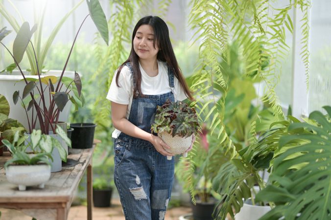 Asian female moving around pots of plants at work
