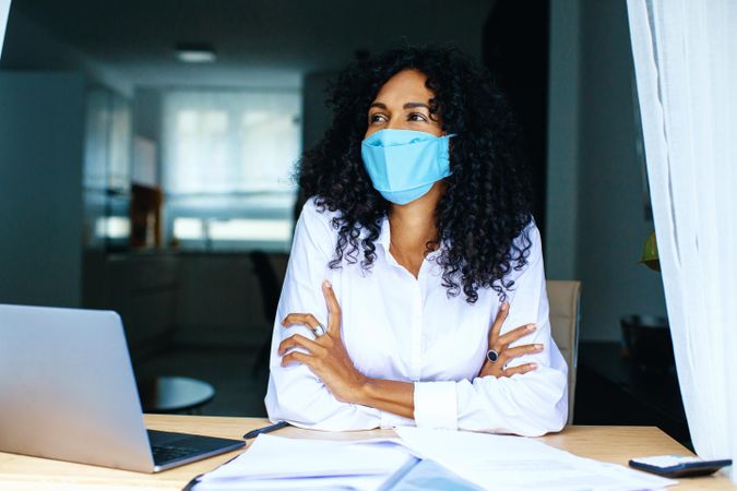 Woman smiling under a facemask while working on documents