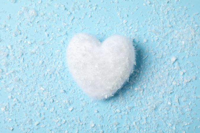 Snow and decorative heart on blue background, space for text