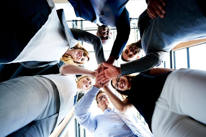 Shot looking up at colleagues smiling in a huddle