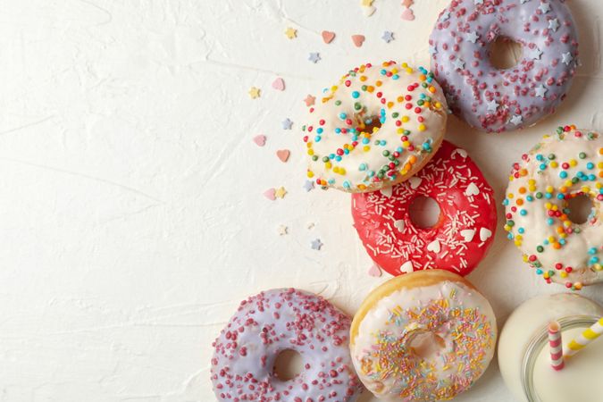 Milk and tasty donuts on plain background, top view