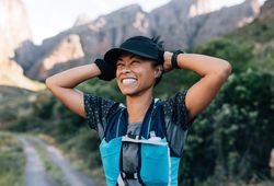 Laughing woman hiker holding cap enjoying the view
