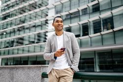 Man using smartphone leaning against wall