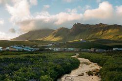 Wooden houses in green mountain valley under cloudy sky