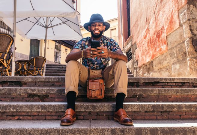 Stylish Black man in the city street using smartphone