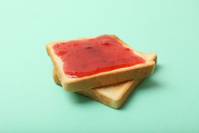 Toasts with strawberry jam on mint background, close up
