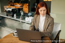 Woman in blazer working on laptop in cafe with coffee 0vllZ4