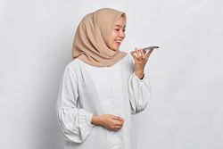 Asian Muslim woman having a nice conversation on her cell phone using the speaker phone