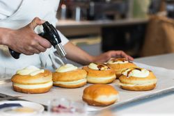 Crop cook burning cream on dessert with gas burner in bakery
