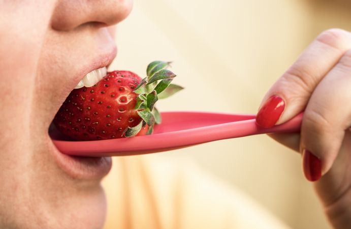 Woman eating strawberry from spoon