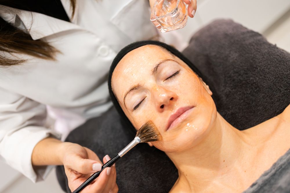 Woman having facial product brushed on face